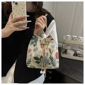 Detail of floral linen bucket bag with chain strap and elegant pearl charms