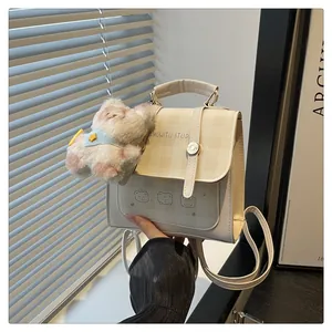 Detail of a beige handbag featuring plaid patterns, cartoon bear prints, and a plush dog charm