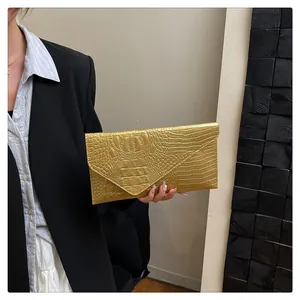 Detailed view of the bright gold envelope clutch bag featuring realistic crocodile embossing