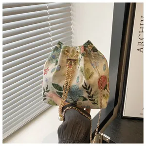 Detail of floral jacquard bucket bag with gold chain strap and large pearl charm