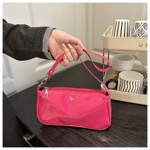 Detail of rose pink patent leather underarm bag with silver zipper and metallic hardware