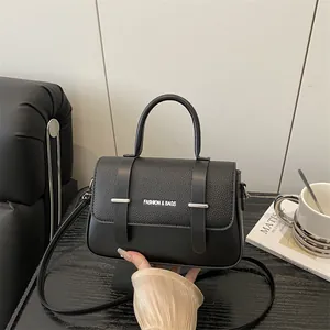 Sac à main minimaliste noir avec détails argentés posé sur un canapé en cuir moderne