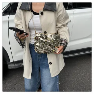 Dettaglio di una borsa a tracolla con paillettes dorate indossata da una modella all'aperto