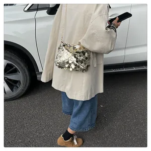 Dettaglio di una borsa a tracolla con paillettes luccicanti e sottile catena in metallo oro