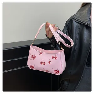 Detail der rosa Schultertasche mit Kirschmuster und verstellbarem goldenem Trageriemen
