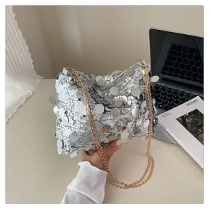 Dettaglio borsa a paillettes argento con tracolla a catena dorata e zip