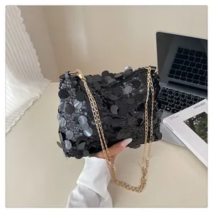 Dettaglio borsa a paillettes nere con tracolla a catena dorata e cerniera lucida