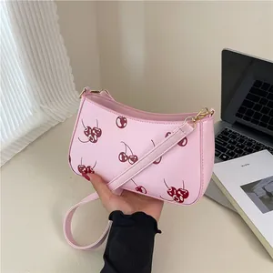 Rosa Schultertasche mit Kirschmuster und goldenen Details in Lifestyle-Umgebung