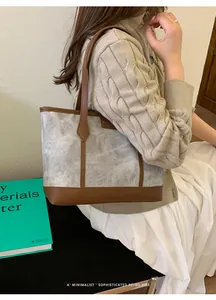 Detail of grey textured tote bag with brown leather trim worn by a model in casual wear