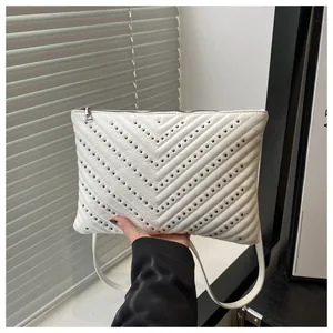 Detail van witte kunstleren crossbodytas met V-vormig quiltwerk en klinknagels