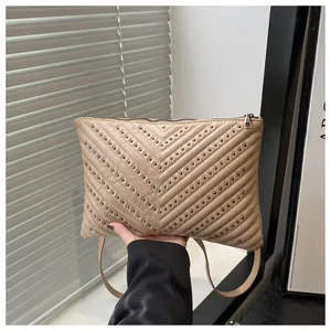 Detail van de V-vormige quilting en metalen studs op deze latte-kleurige lederen tas