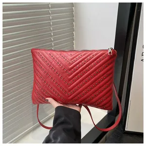 Detail van de rode gewatteerde crossbodytas met zilveren studs en leerstructuur