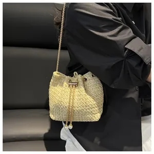 Dettaglio borsa a secchiello intrecciata con catena dorata e ciondoli con perle