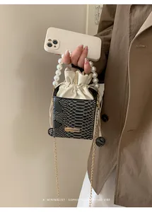 Dettaglio della mini borsa a secchiello pitonata con manico di perle e catena d'oro
