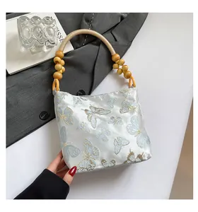 Dettaglio della borsa tote in raso azzurro con ricamo a farfalla e perline di legno fine