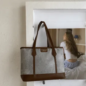 Vintage canvas tote bag with grey textured finish and brown leather trim in home setting