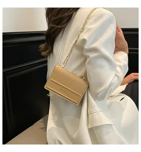 Dettaglio della borsa a tracolla beige con texture verticale e catena dorata