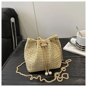 Dettaglio della borsa a secchiello in paglia con catena dorata e coulisse di perle