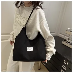 Detail of minimalist black corduroy tote bag featuring an original design fashion label