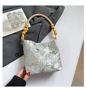 Dettaglio del tessuto jacquard floreale e manico in corda con perline su borsa blu