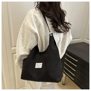 Detail of minimalist black canvas tote bag with a white fashion patch for daily commute