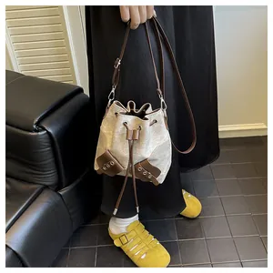 Détail du sac seau en toile avec bordure en cuir marron et cordon sur le mannequin