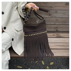 Détail du sac bandoulière en daim marron foncé avec rivets dorés et franges bohèmes