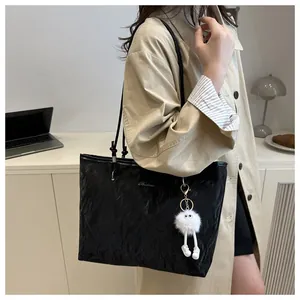 Detail of black large capacity tote bag with plush charm and stylish leather texture