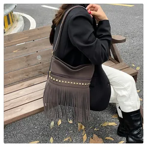 Détail du sac à bandoulière en daim marron avec clous dorés et longues franges