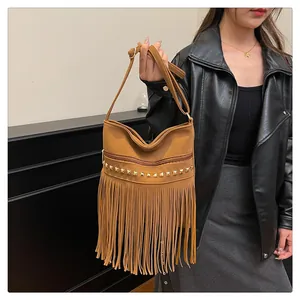 Détail du sac en daim marron avec clous dorés et longues franges de style bohème