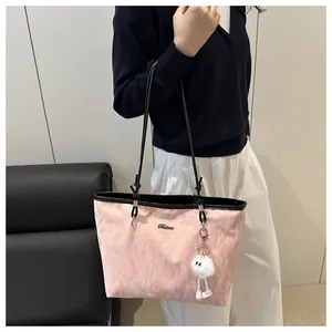 Pink tote bag detail with black handles and cute white plush ball charm on a model