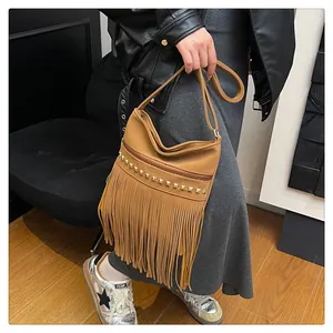Détail d'un sac à bandoulière marron vintage avec longues franges et clous dorés