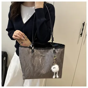 Detail of grey crinkled tote bag with soft plush charm and spacious interior being used