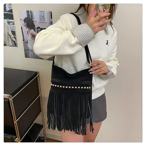 Détail du sac à franges en daim noir avec clous dorés portés en bandoulière par un mannequin