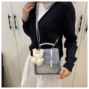 Détail du sac à bandoulière en denim bleu et cuir argenté avec charme d'ours en peluche