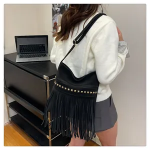 Détail du sac bandoulière en daim noir avec de longues franges et clous dorés