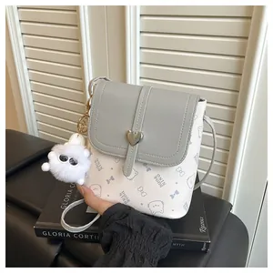 Close-up of mini bucket bag with heart lock, cat print, and plush charm detail