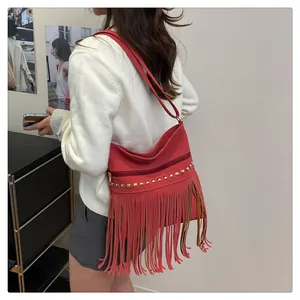 Détail du sac à bandoulière rouge avec franges, clous dorés et fermeture éclair sur mannequin