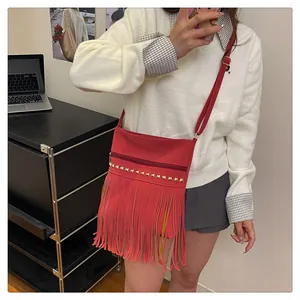 Détail du sac bandoulière en cuir rouge avec clous dorés et longues franges de glands