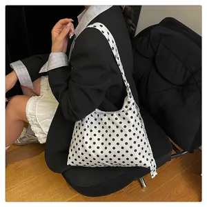 Polka dot hobo bag styled with black blazer and white skirt shown on shoulder