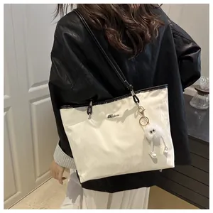 White large capacity tote bag with black handles and plush charm shown on model