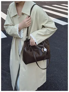 Close-up of large dark brown tote bag featuring metal fashion plate and baseball charm