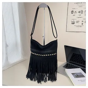 Détail du sac bandoulière noir avec rivets dorés et franges dans un décor minimaliste