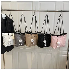 Row of colorful textured tote bags featuring soft fabric and plush doll charms