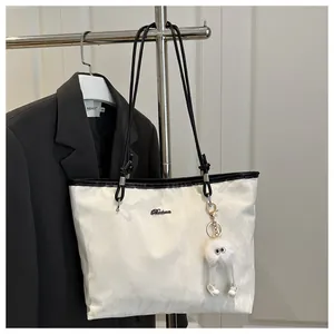 Close-up of white tote bag texture with black leather straps and plush pompom charm