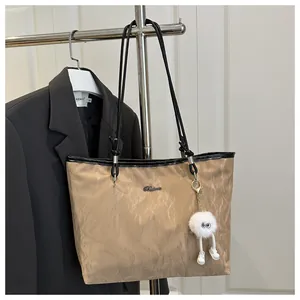 Macro shot of dark khaki tote bag featuring wrinkled texture and plush pendant charm