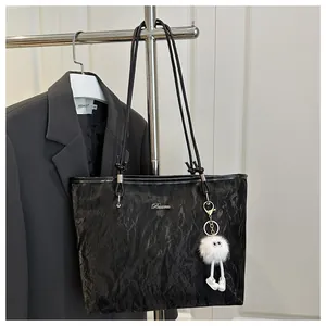 Close-up of black crinkle texture tote bag with metal logo and plush charm