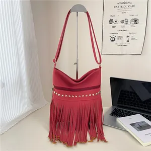 Sac bandoulière rouge en similicuir avec clous dorés et longues franges sur support
