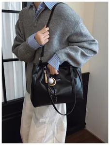 Detail view of large black matte PU leather tote bag with fashion tag and baseball charm