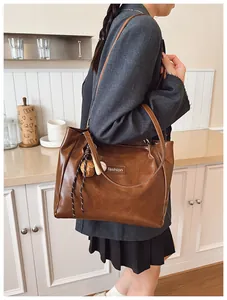 Detail of dark brown leather tote bag with fashion tag and baseball charm ornament